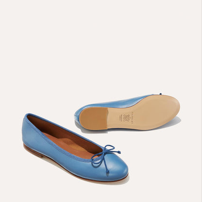 The Demi in cerulean blue nappa, a comfortable ballet flat with a rounded toe and adjustable cord bow detail.