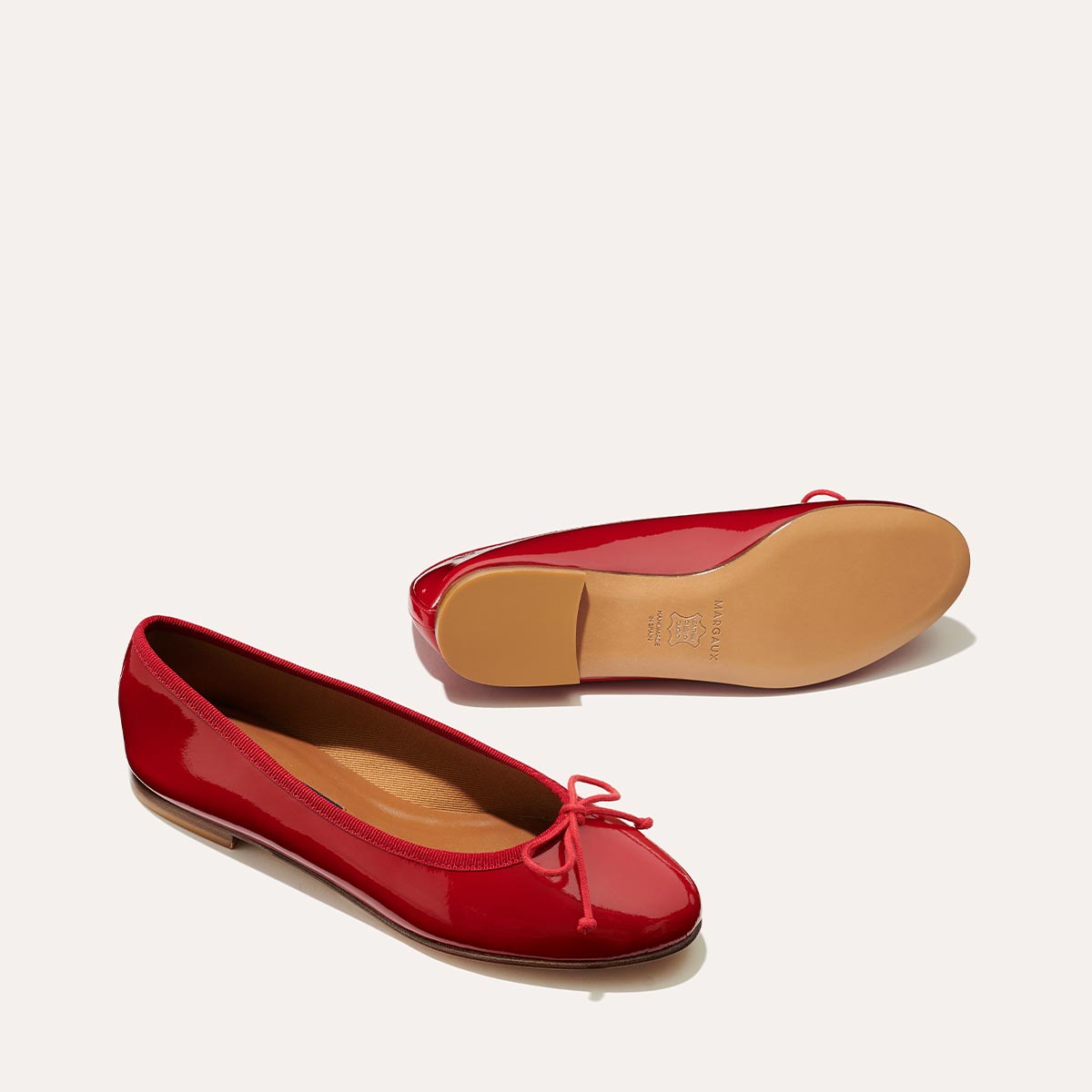 The Demi in Cherry Patent, a comfortable ballet flat with a rounded toe and adjustable cord bow detail.