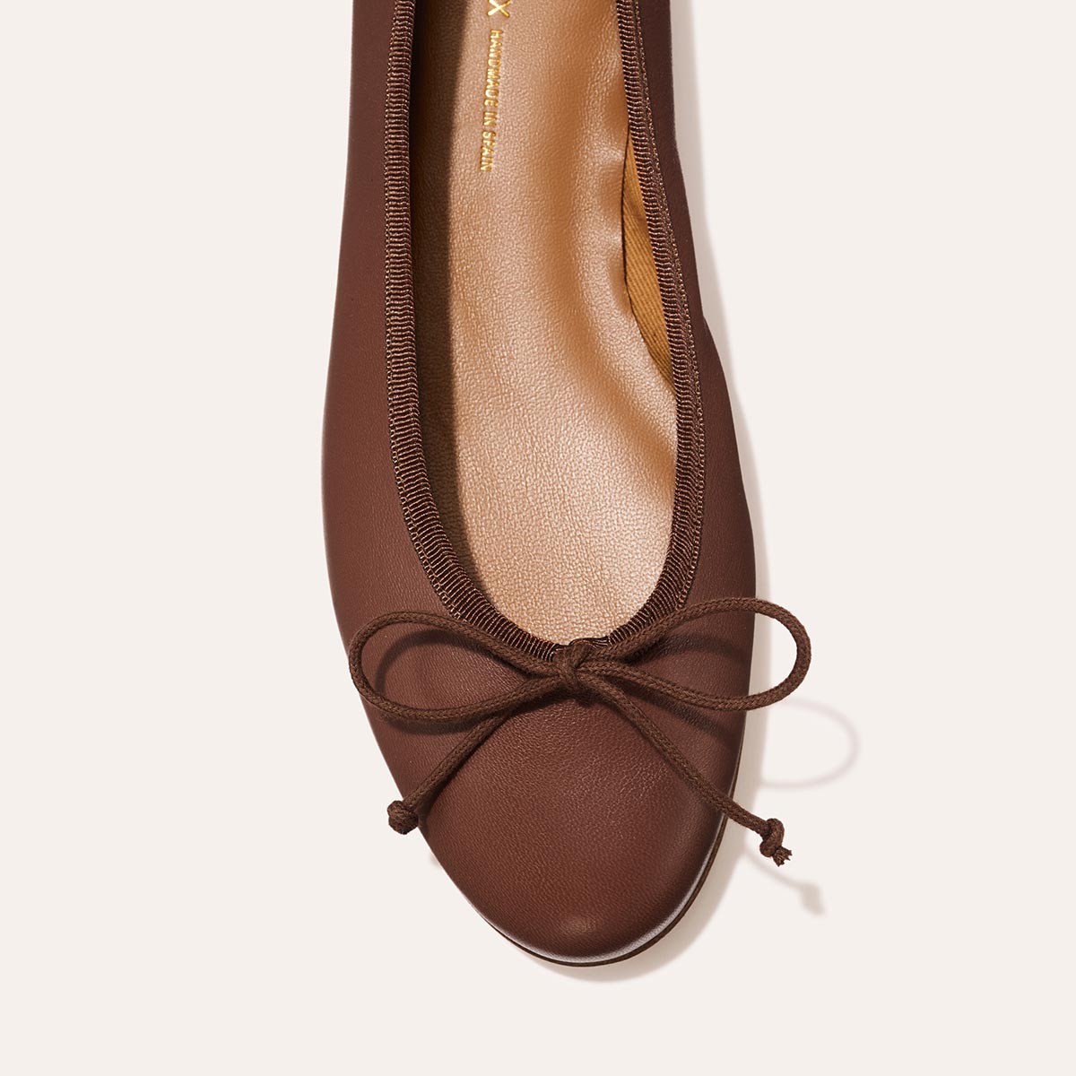 Handmade in Spain, The Demi - Cognac Nappa is a comfortable brown leather ballet flat featuring a rounded toe and a thin matching bow.