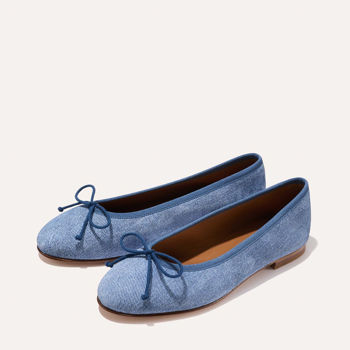 The Demi in soft Denim Suede, a comfortable ballet flat with a rounded toe and adjustable cord bow detail.