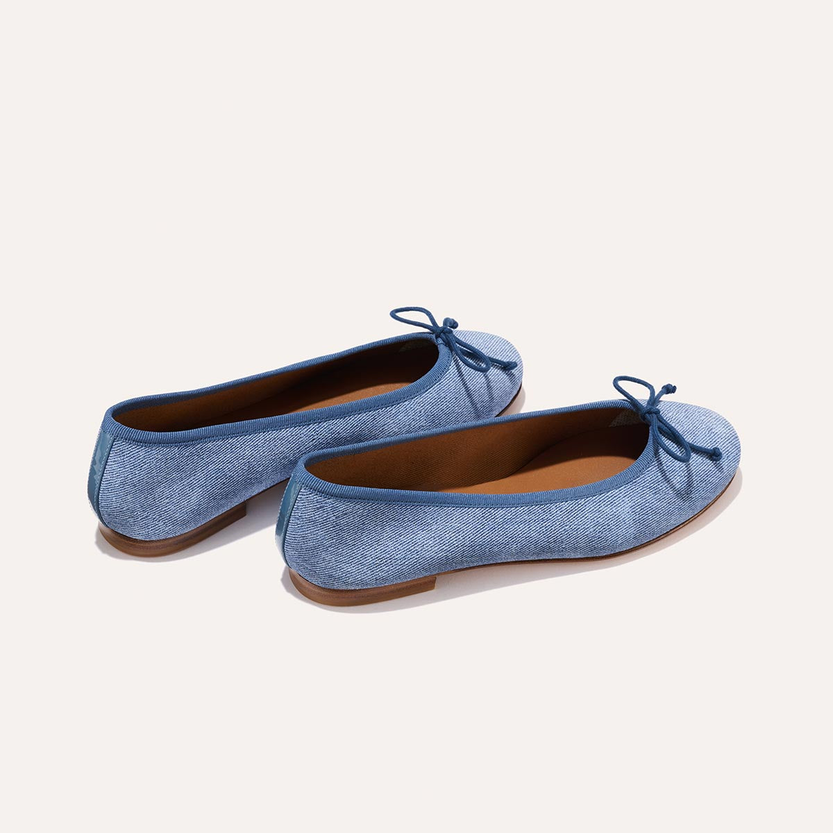 The Demi in soft Denim Suede, a comfortable ballet flat with a rounded toe and adjustable cord bow detail.