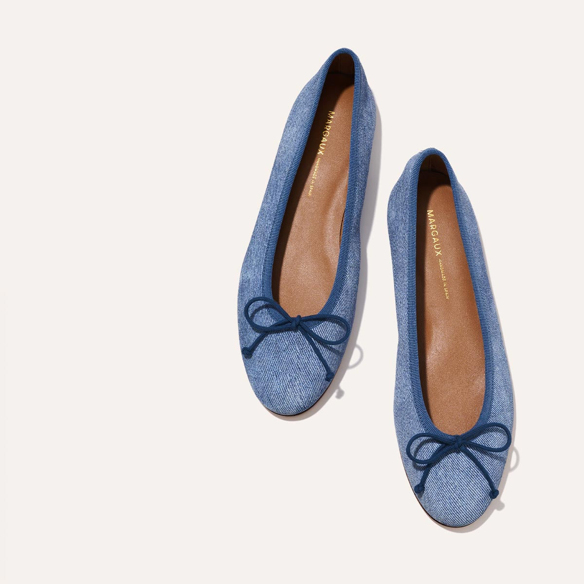 The Demi in soft Denim Suede, a comfortable ballet flat with a rounded toe and adjustable cord bow detail.