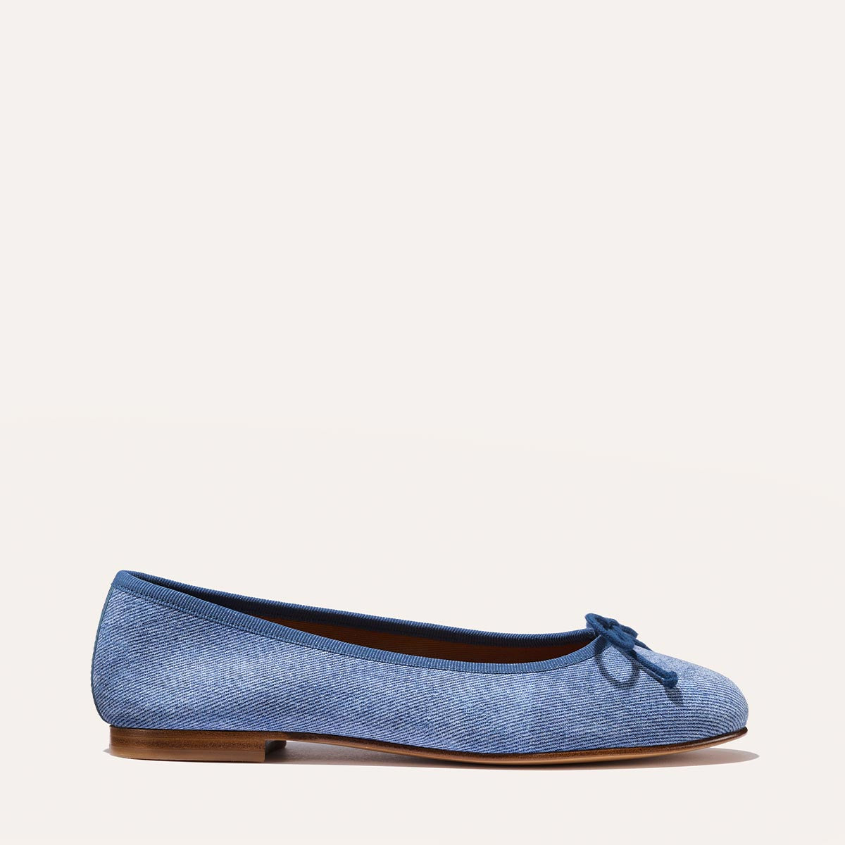 The Demi in soft Denim Suede, a comfortable ballet flat with a rounded toe and adjustable cord bow detail.