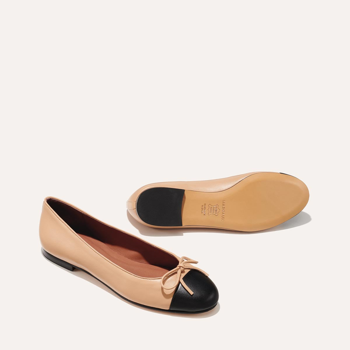 The Demi in Dune Nappa with a black cap-toe detail, a comfortable ballet flat with a rounded toe and adjustable cord bow detail.