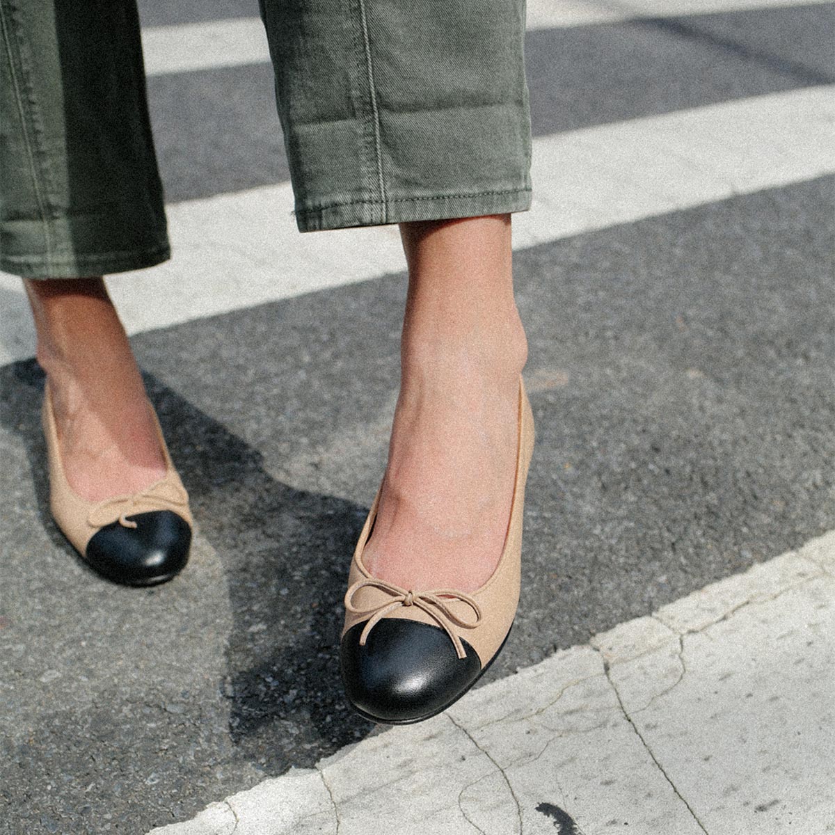 The Demi in Dune Nappa with a black cap-toe detail, a comfortable ballet flat with a rounded toe and adjustable cord bow detail.