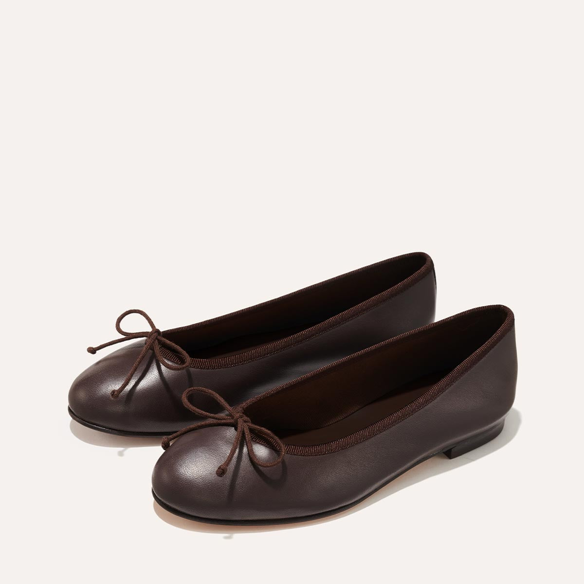 The Demi in Espresso Nappa, a comfortable ballet flat with a rounded toe and adjustable cord bow detail.