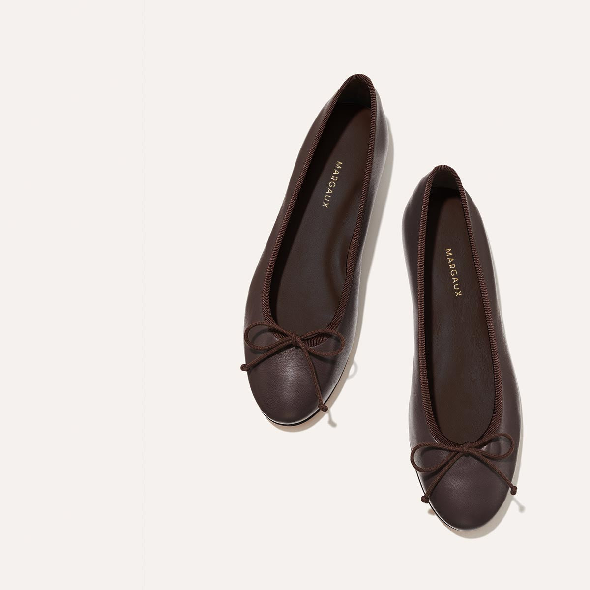 The Demi in Espresso Nappa, a comfortable ballet flat with a rounded toe and adjustable cord bow detail.