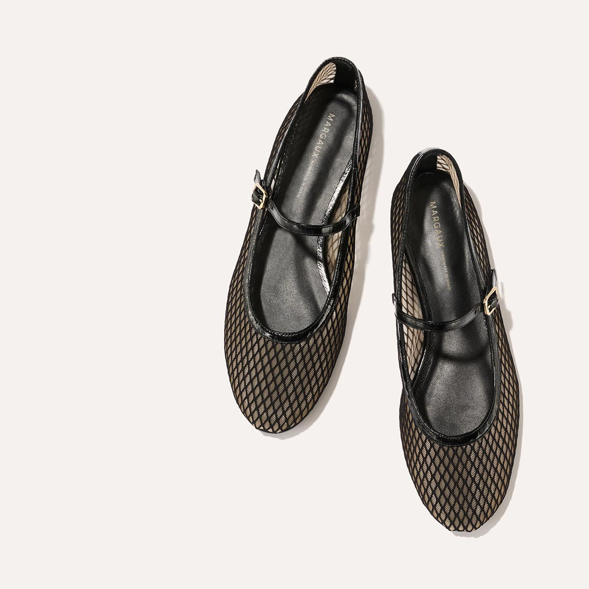 The Demi Jane in Black Fishnet Mesh, a sheer ballet flat with a rounded toe and an adjustable strap for a secure fit.