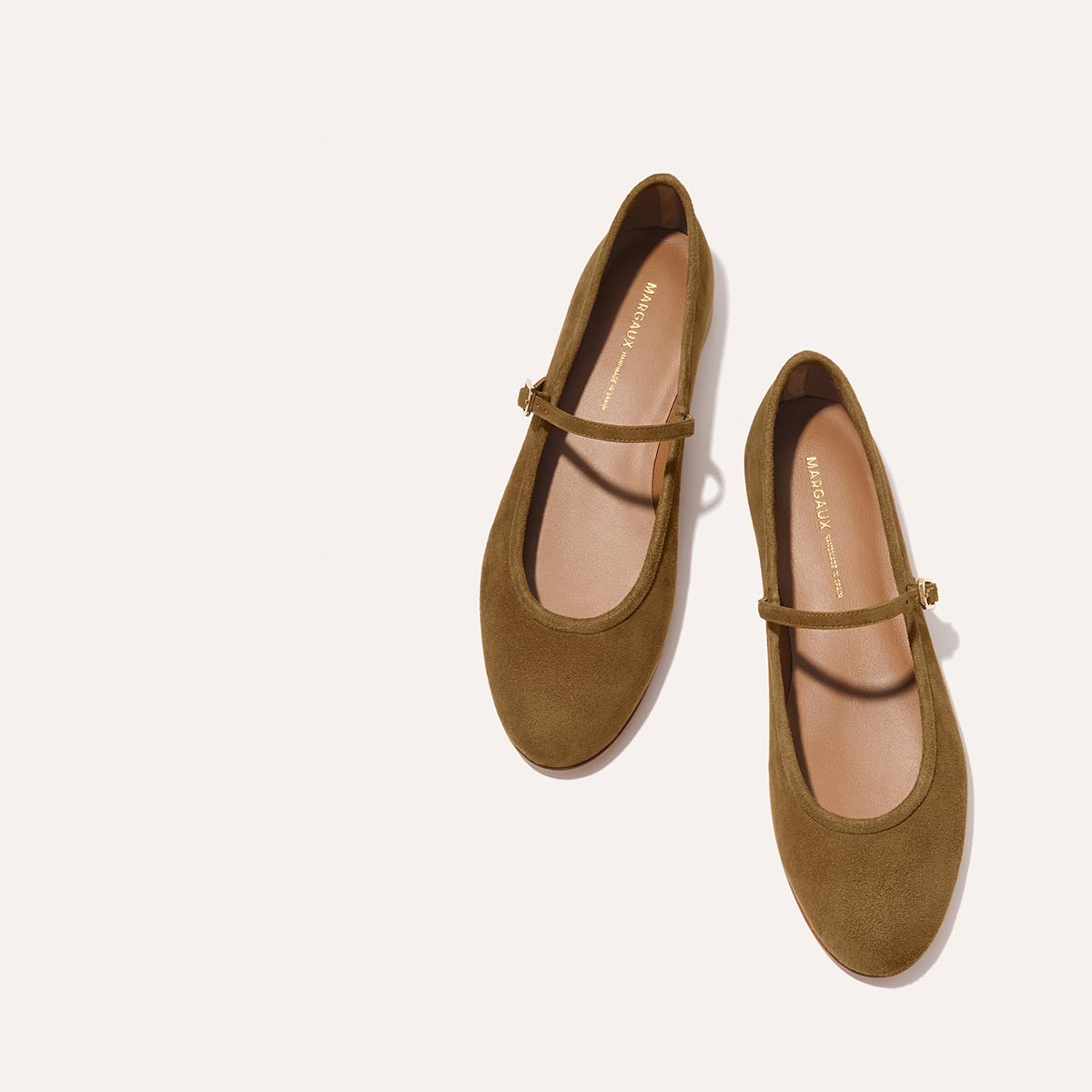 The Demi Jane - Cedar Suede by margaux-development: brown suede Mary Jane flats featuring rounded toes and thin buckle straps, shown on a light beige background.