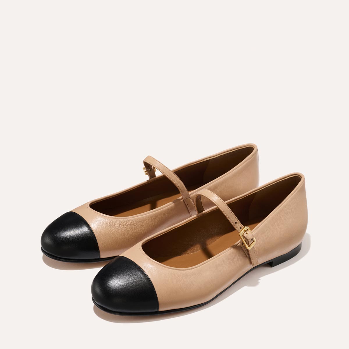 The Demi Jane in smooth Dune nappa leather, a ballet flat with a rounded toe, black cap-toe detail  and an adjustable strap for a secure fit.