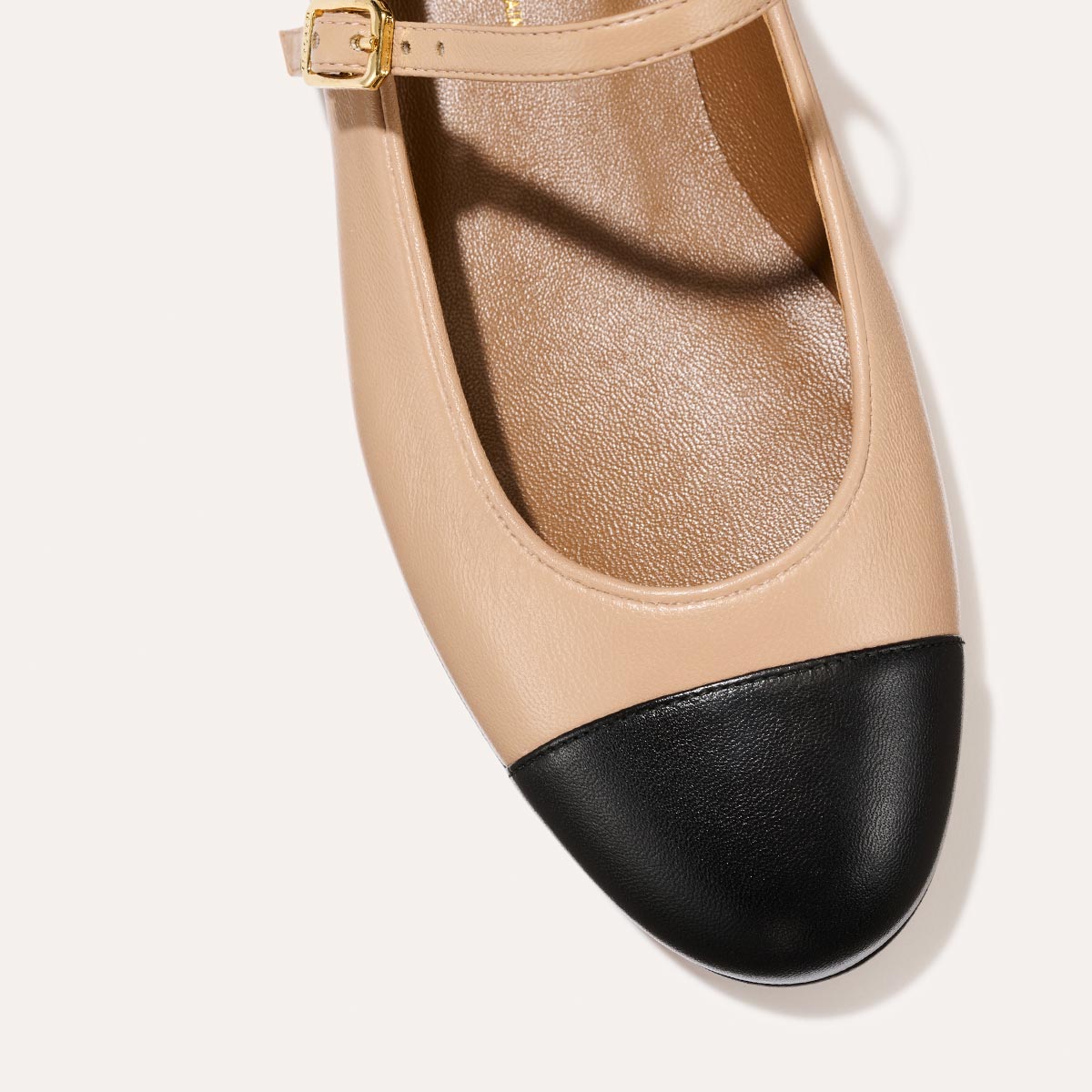 The Demi Jane in smooth Dune nappa leather, a ballet flat with a rounded toe, black cap-toe detail  and an adjustable strap for a secure fit.