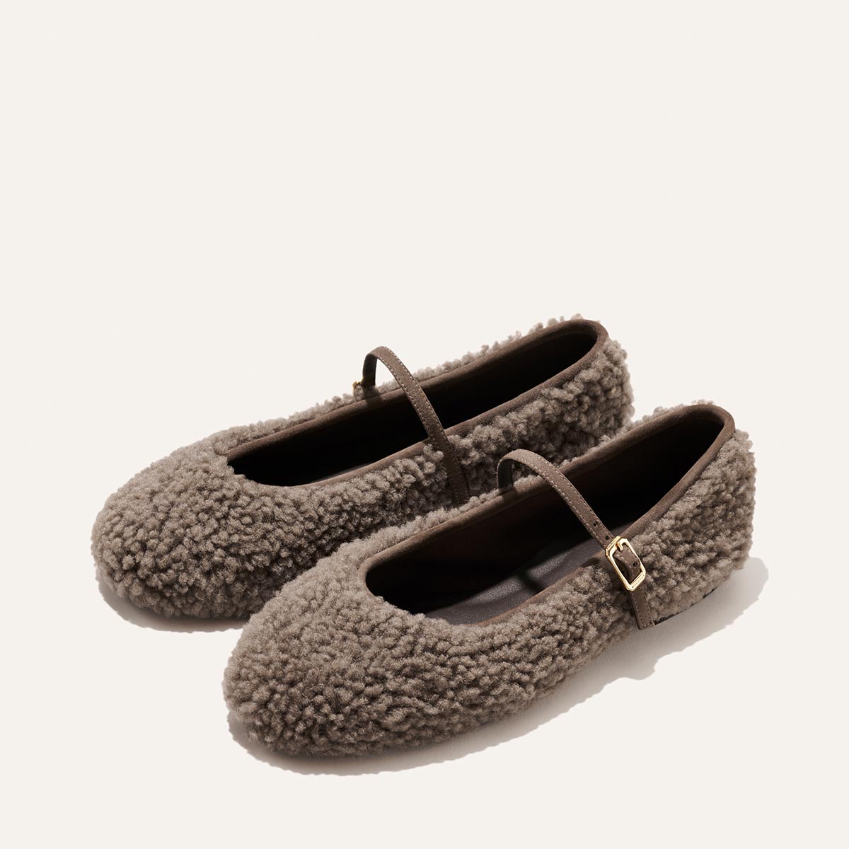 The Demi Jane - Taupe Shearling Mary Jane flats feature a thin buckled strap, offering an air of elegant femininity.
