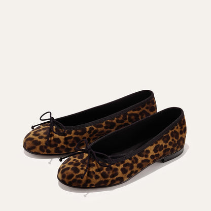 The Demi - Leopard Suede by margaux-development: Handmade in Spain, these comfortable ballet flats feature leopard print suede, black trim, bow accents on the toes, and flat black soles—shown against a light background.
