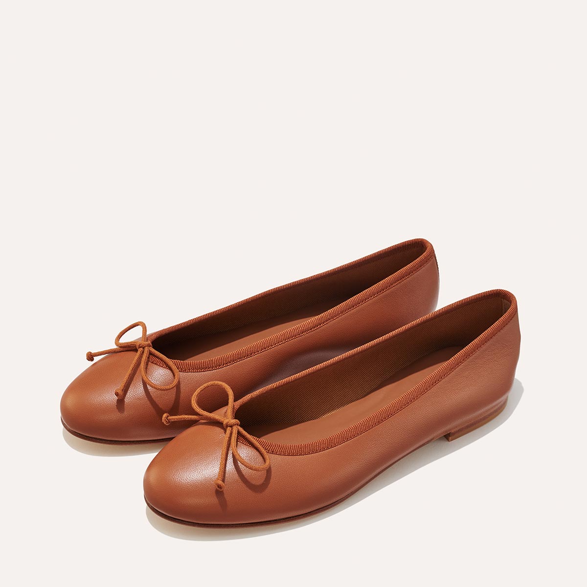 The Demi in Saddle Nappa, a comfortable ballet flat with a rounded toe and adjustable cord bow detail.