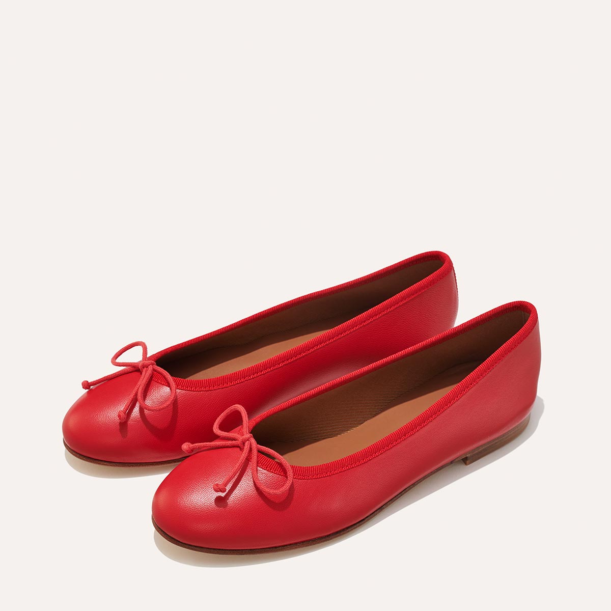 The Demi in Scarlet Nappa, a comfortable ballet flat with a rounded toe and adjustable cord bow detail.