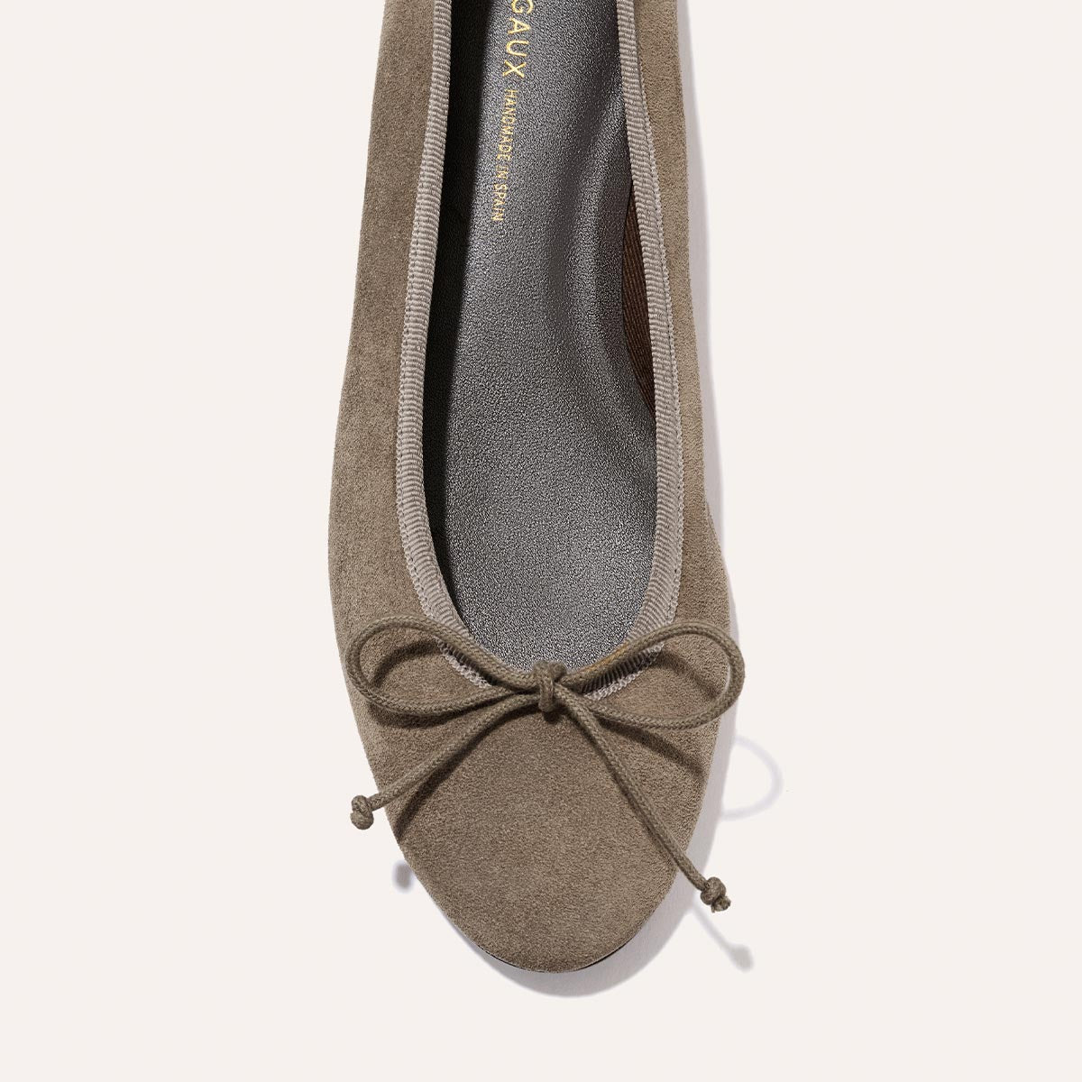 Close-up of Margaux’s The Demi - Truffle Suede ballet flat, handmade in Spain with taupe suede, a rounded toe, and a front bow for comfort.