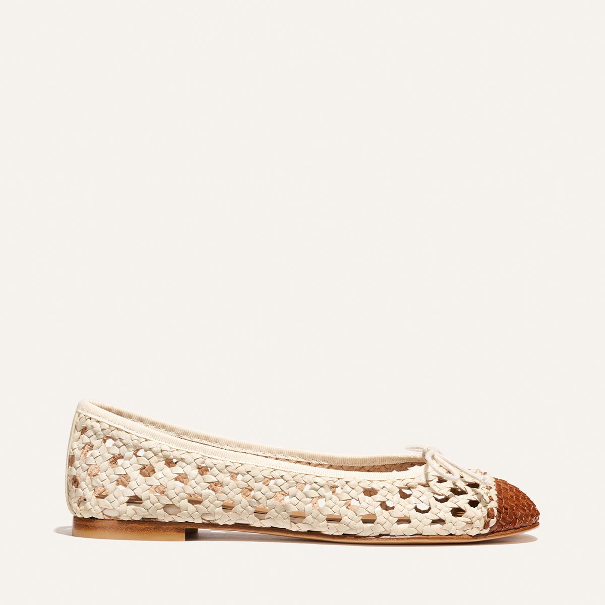 The Demi - Ecru and Saddle Woven Leather by Margaux is a cream woven flat shoe with a brown toe and bow detail, shown in profile against a plain light background.