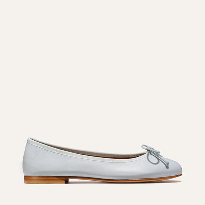 The Demi - Mist Blue Nappa by Margaux is a handmade ballet flat from Spain, featuring a small toe bow, low wooden heel, and smooth leather finish, shown in profile against a plain light background.
