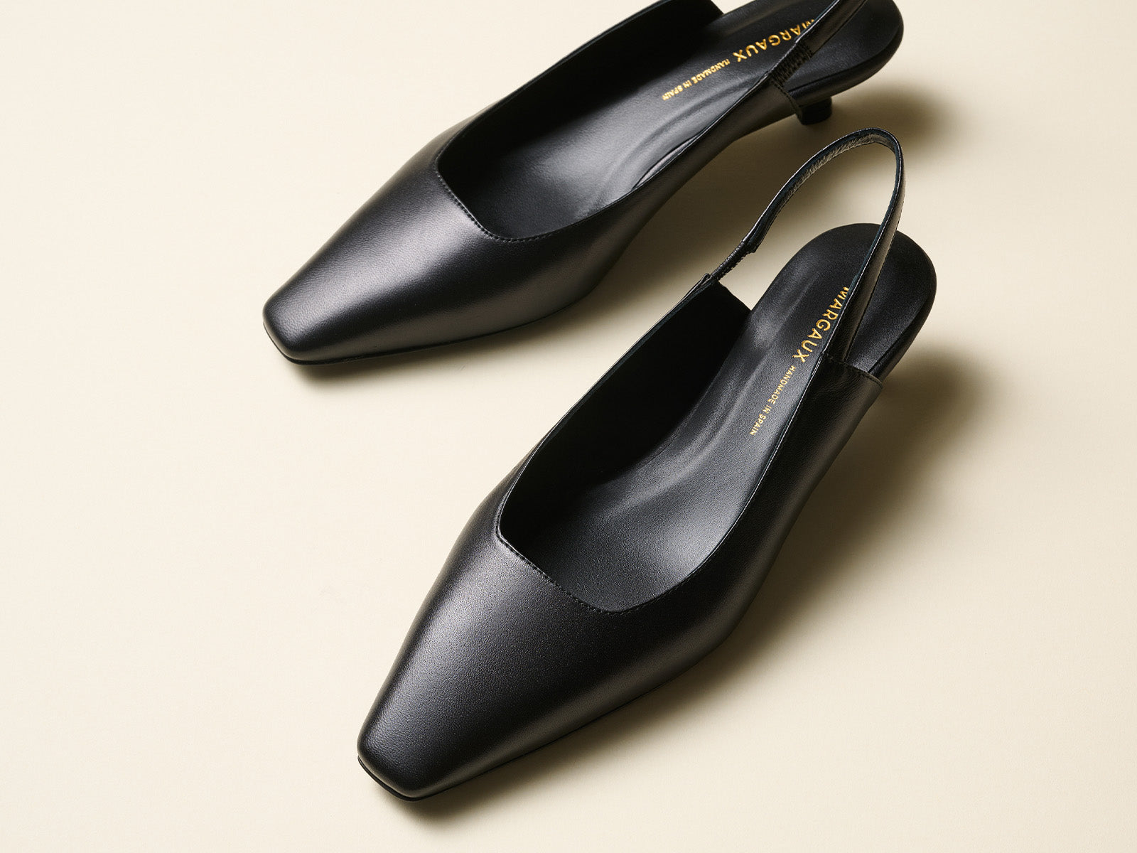 Pair of black shoes with a brand name on a beige background