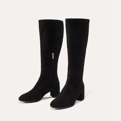 The Edie Boot in Black Suede, a sleek knee-high silhouette complemented by a comfortable 2.5-inch block heel and a hidden interior zipper for a fitted look.
