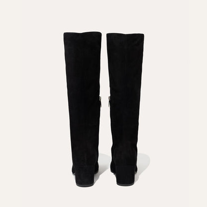 The Edie Boot in Black Suede, a sleek knee-high silhouette complemented by a comfortable 2.5-inch block heel and a hidden interior zipper for a fitted look.