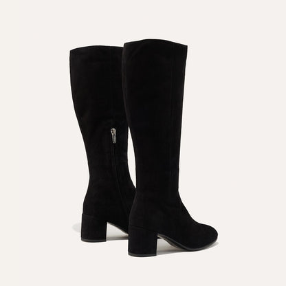 The Edie Boot in Black Suede, a sleek knee-high silhouette complemented by a comfortable 2.5-inch block heel and a hidden interior zipper for a fitted look.