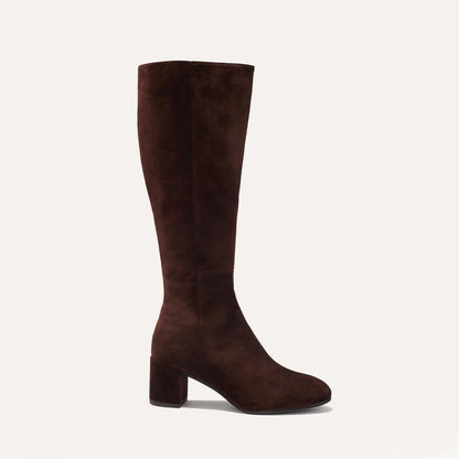 The Edie Boot in Chocolate Suede, a sleek knee-high silhouette complemented by a comfortable 2.5-inch block heel and a hidden interior zipper for a fitted look.