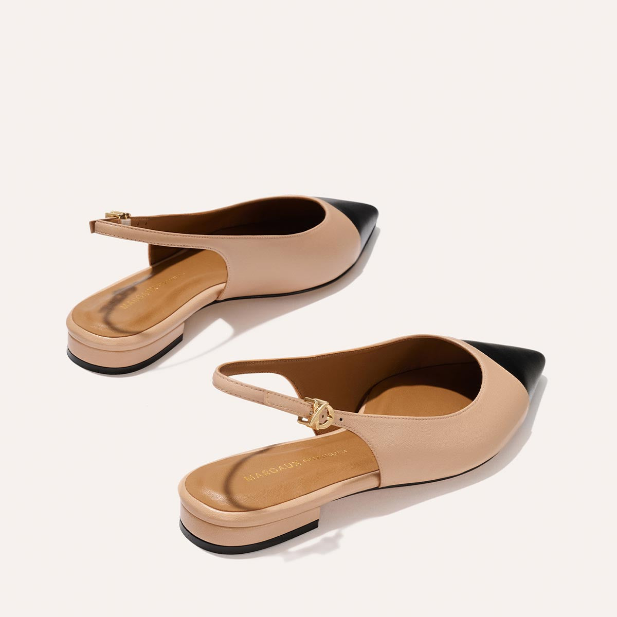 The Elise by margaux-development: beige pointed-toe slingback shoes with black toes, low block heels, and a leather sole in Dune and Black Nappa, displayed on a light background.