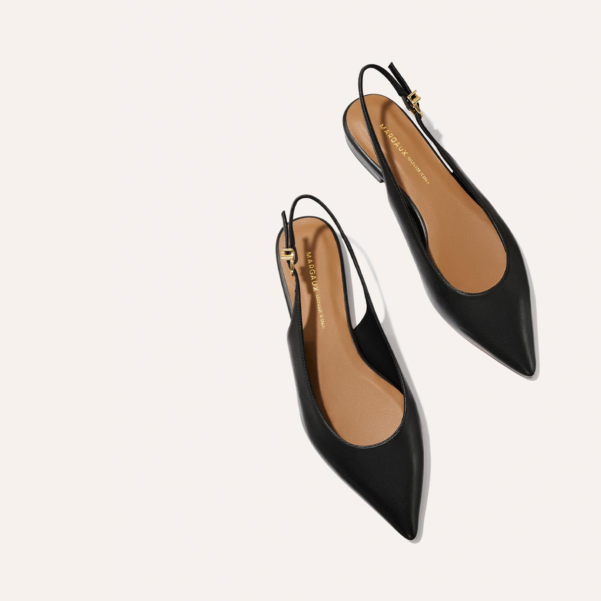 The Elise - Black Nappa by margaux-development: black leather slingback flats with pointed toes and tan insoles, shown on a light background.