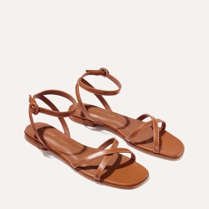 The Flat Sandal in saddle brown nappa, a minimal sandal featuring thin, flattering straps with a subtly square toe.