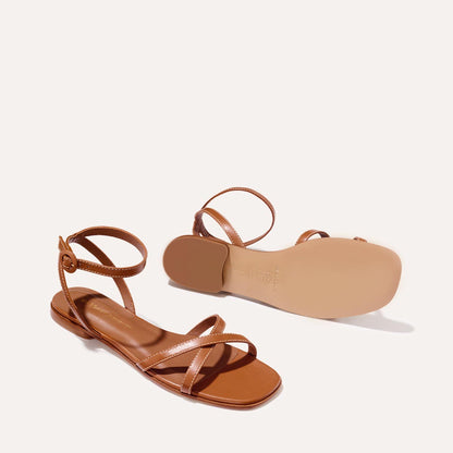 The Flat Sandal in saddle brown nappa, a minimal sandal featuring thin, flattering straps with a subtly square toe.