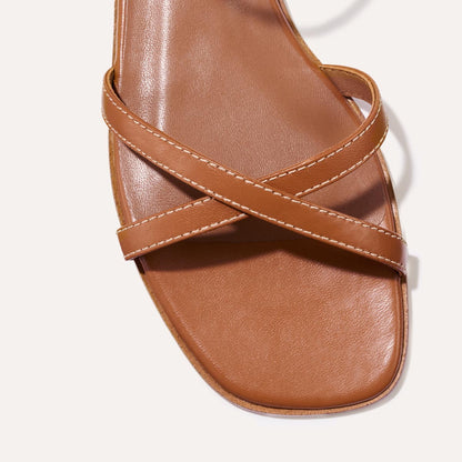 The Flat Sandal in saddle brown nappa, a minimal sandal featuring thin, flattering straps with a subtly square toe.