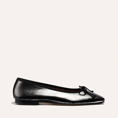 The Fonteyn by Margaux in Black Crinkle-Gloss Nappa is a ballet flat featuring a rounded toe, low heel, and small bow detail, shown against a plain light background.