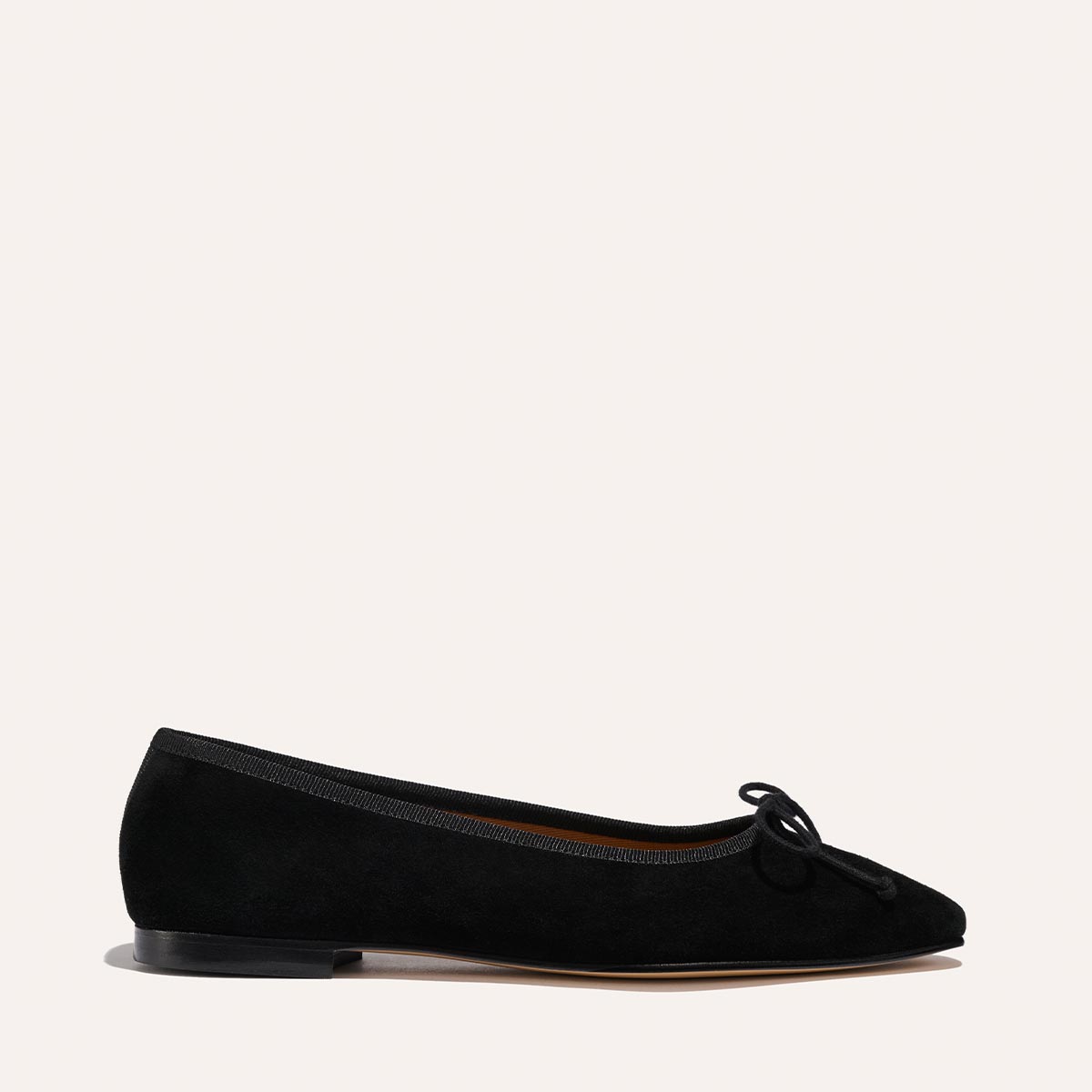 The Fonteyn - Black Suede by Margaux is a handcrafted ballet flat featuring black suede, a small bow on the rounded toe, low heel, and comfort-focused design, shown in side profile against a plain light background.