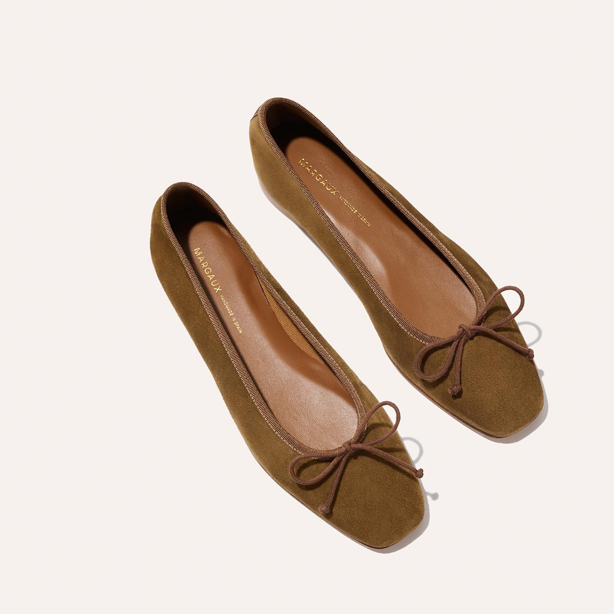 The Margaux Fonteyn - Cedar Suede are brown suede ballet flats with square toes, brown bow accents on the front, and tan insoles, shown on a light background.