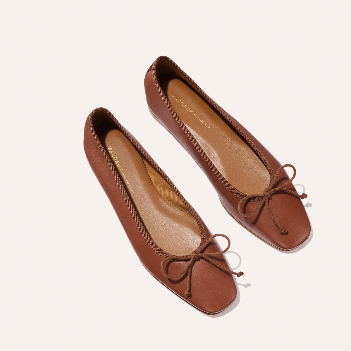 The Fonteyn - Cognac Nappa by Margaux: brown leather ballet flats with square toes and bow accents, displayed on a light background.
