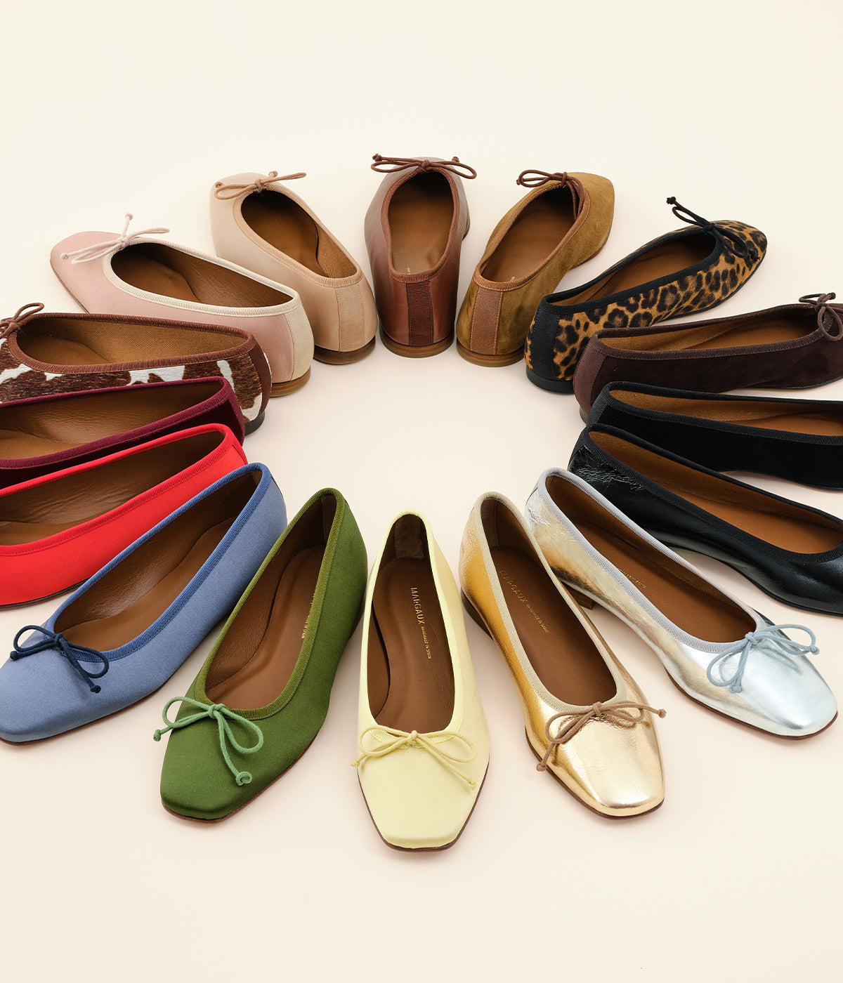A semicircle arrangement of various ballet flats in different colors and patterns, including green, yellow, red, blue, animal print, metallic silver and gold, brown, black, and beige, displayed on a light background.