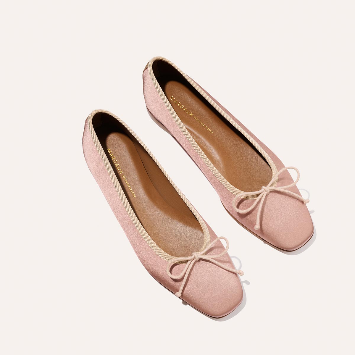 The Fonteyn - Dusty Pink Satin by Margaux: handcrafted ballet flats in light pink satin, featuring square toes and delicate bows for a comfort-first fit, displayed on a plain light background.