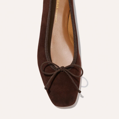 Close-up of Margaux's The Fonteyn in Espresso Suede—a comfort-first ballet flat with a squared-off toe and matching brown bow, seen from above against a light background.