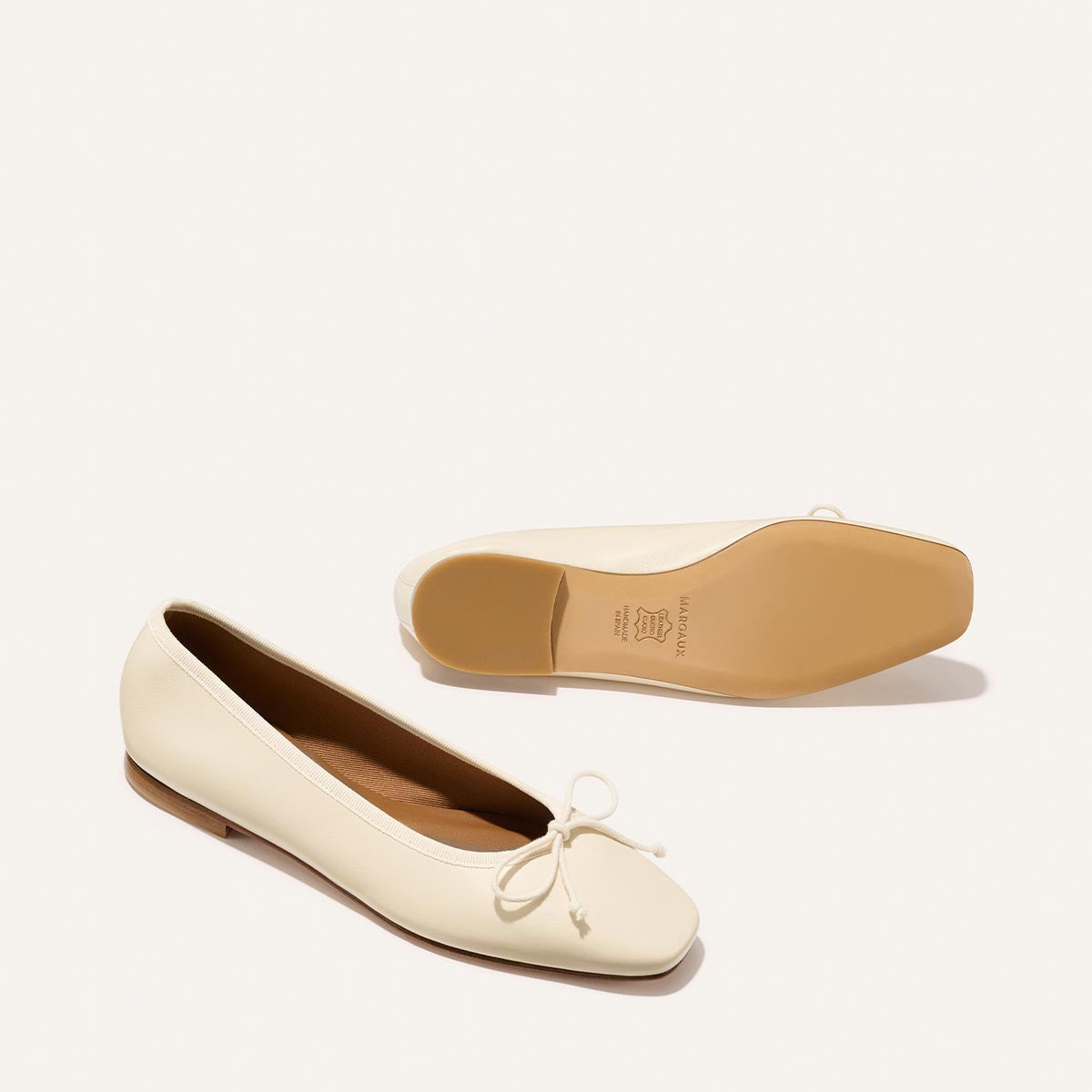 White flat shoe with a bow on a light beige background