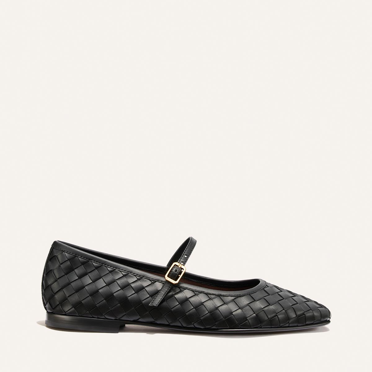 The Fonteyn Jane by Margaux in Black Woven Pasado Nappa, a Mary Jane flat featuring a delicate gold buckle strap, is photographed on a plain off-white background.