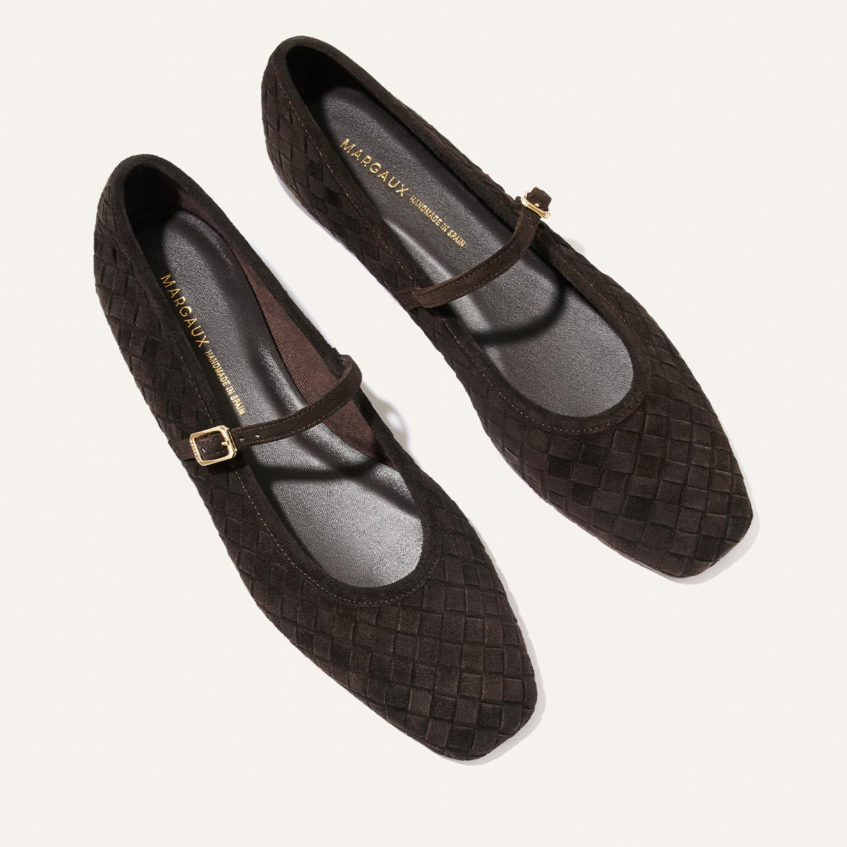 A pair of The Fonteyn Jane flats by Margaux in dark chocolate woven pasado suede, featuring pointed toes and a single strap with a small gold buckle, displayed on a light background.