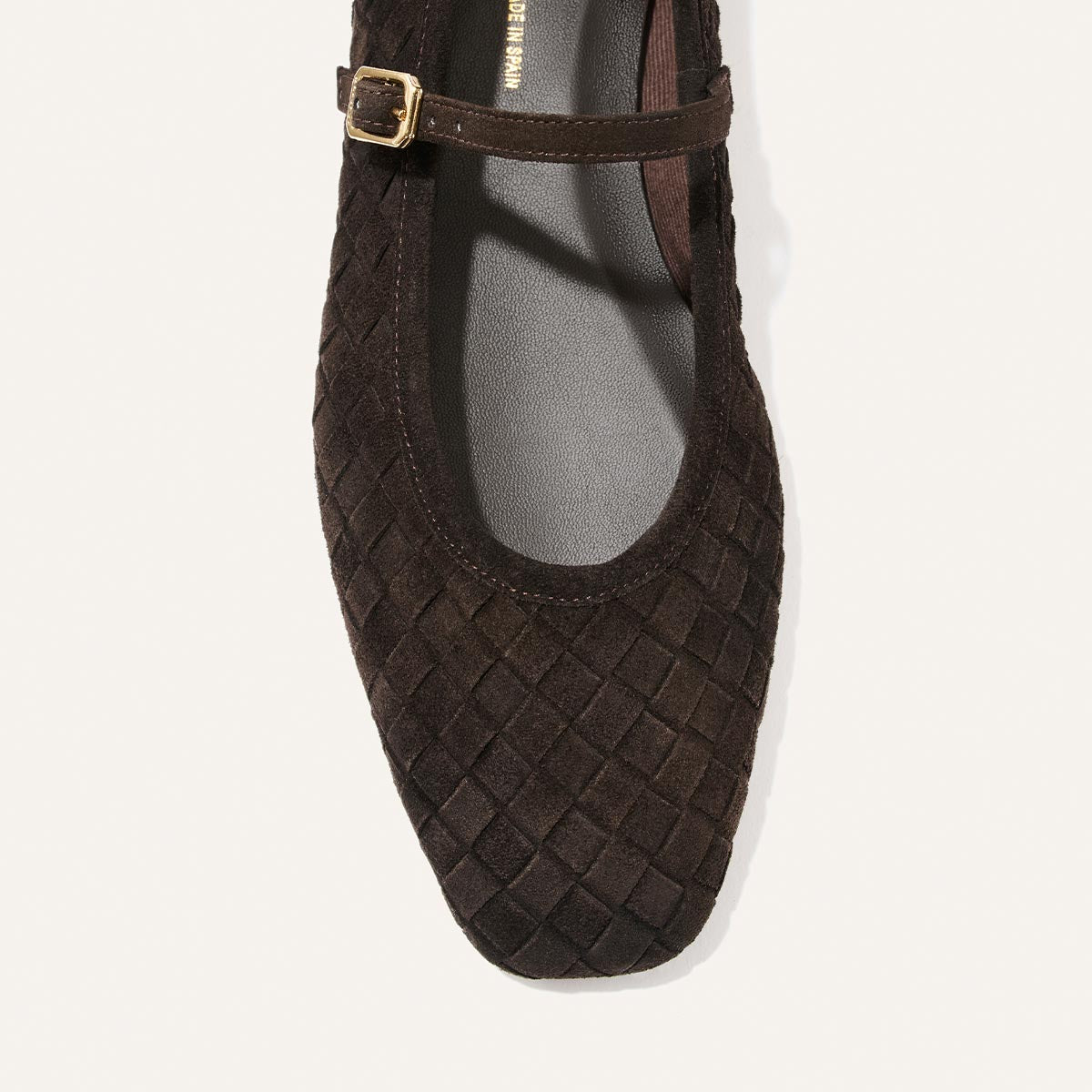 A top view of the Margaux Fonteyn Jane in Dark Chocolate Woven Pasado Suede, featuring a textured suede finish and a gold buckle strap, displayed against a white background.