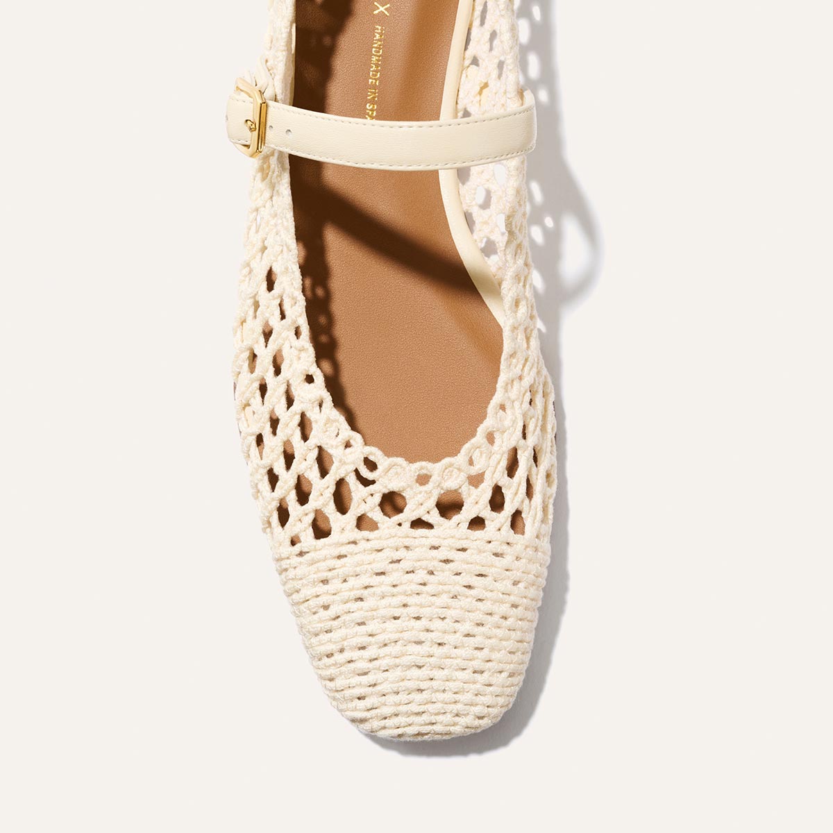 A close-up of Margaux's The Fonteyn Jane in Ecru Macrame, a cream-colored woven ballerina flat with a square toe and cotton macrame design, featuring a thin adjustable strap with a small buckle across the top.