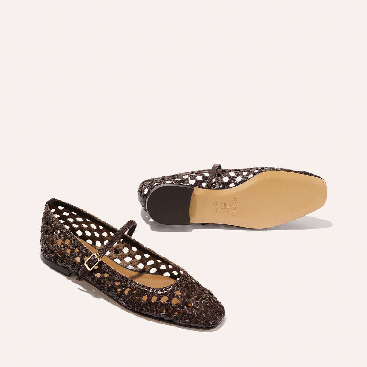 The Fonteyn Jane by Margaux: espresso handwoven leather flats with an adjustable buckle strap, open lattice design, and tan soles—one shoe upright, one on its side displaying the sole; elegant and comfortable ballerina style.