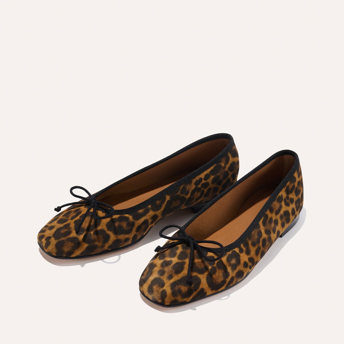 The Fonteyn - Leopard Suede by Margaux: leopard print ballet flats with black trim and a black bow on the toe, shown against a plain white background.