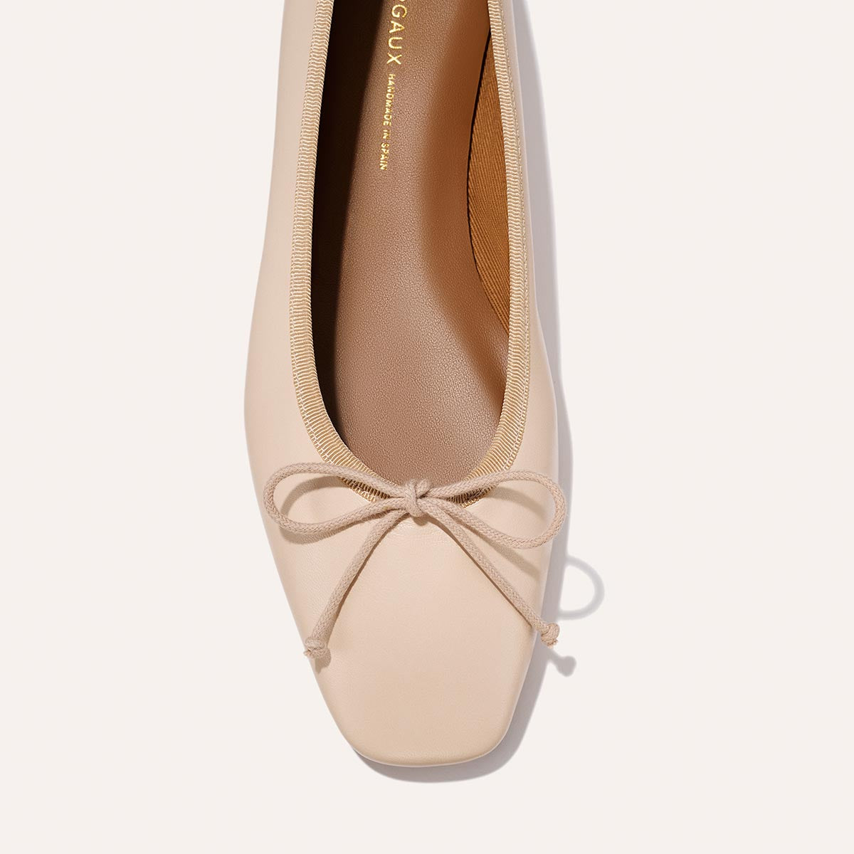 A close-up top view of The Fonteyn - Magnolia Nappa by Margaux, a comfort-first beige ballet flat with a square toe, matching bow detail, slightly darker tan insole, and clean minimalist lines.