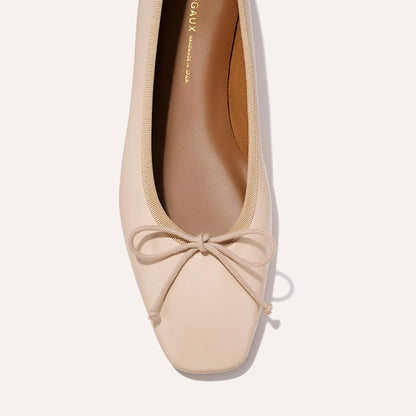 A close-up top view of The Fonteyn - Magnolia Nappa by Margaux, a comfort-first beige ballet flat with a square toe, matching bow detail, slightly darker tan insole, and clean minimalist lines.