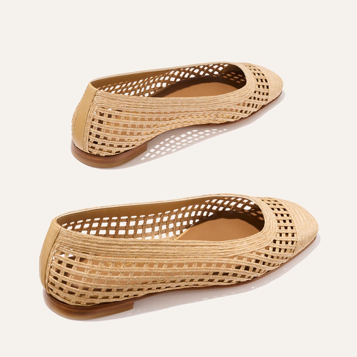 The Fonteyn - Natural Grid Raffia ballet flats by Margaux feature beige woven raffia, pointed toes, open lattice sides, and low brown soles for an elevated yet playful style, showcased on a plain light background.