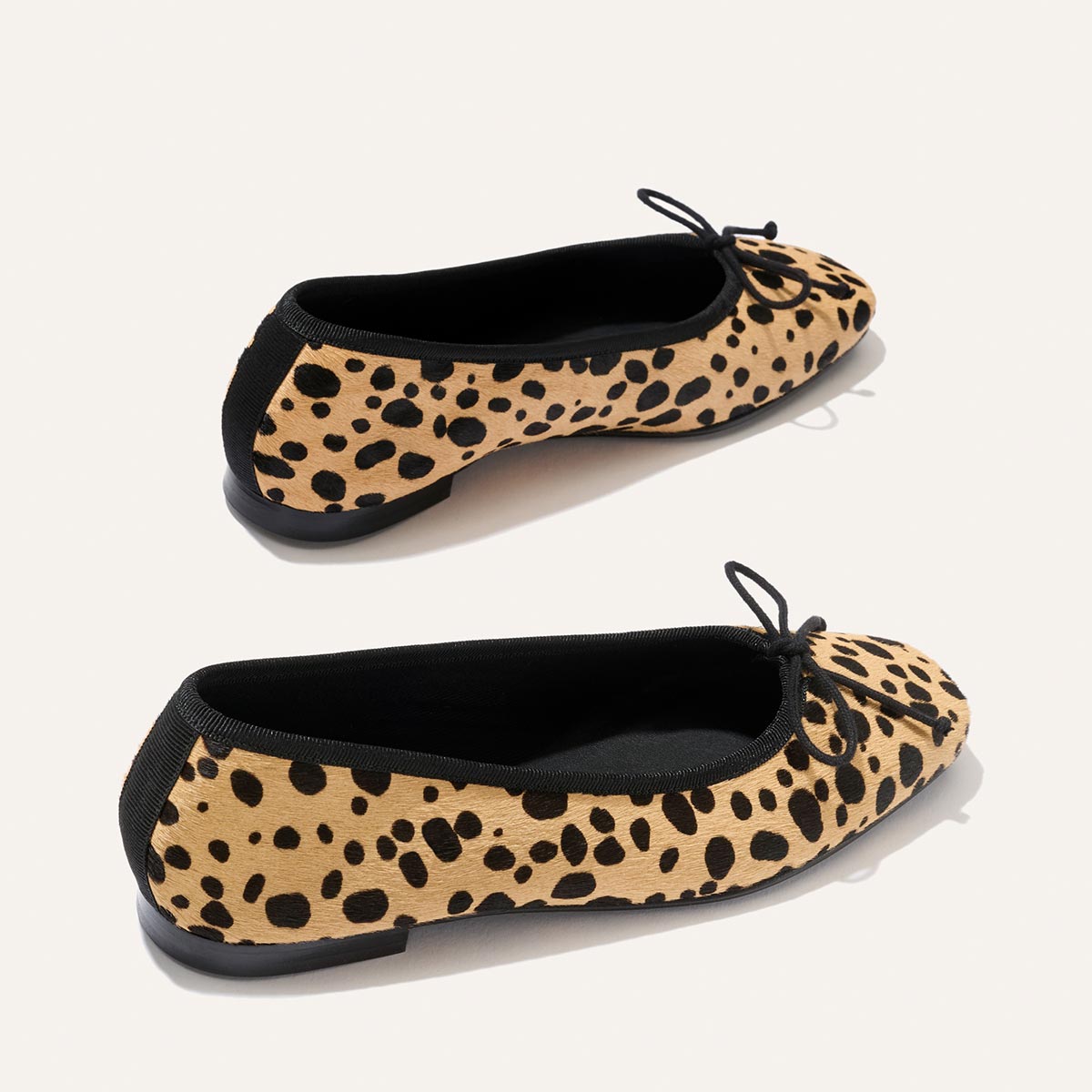 Pair of "The Fonteyn - Tan Cheetah Haircalf" ballet flats by Margaux, featuring stylish cheetah-print haircalf with black trim, delicate toe bows, and flat black soles, are displayed on a light background—delivering comfort-first style ideal for everyday wear.